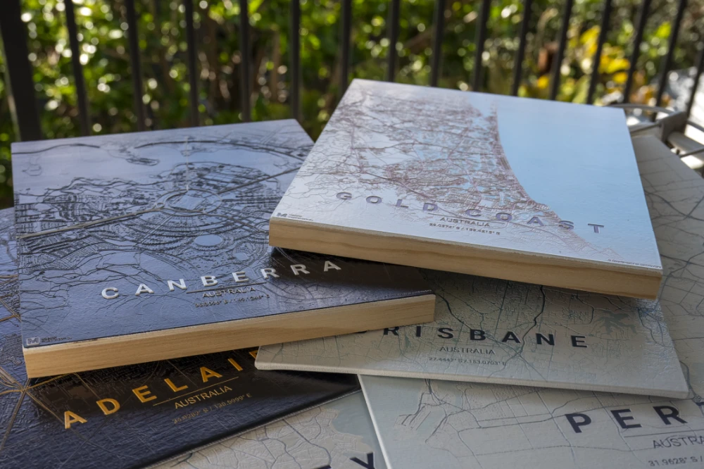 Stacked wood-board maps of Canberra, Gold Coast, Brisbane, Adelaide, and Perth